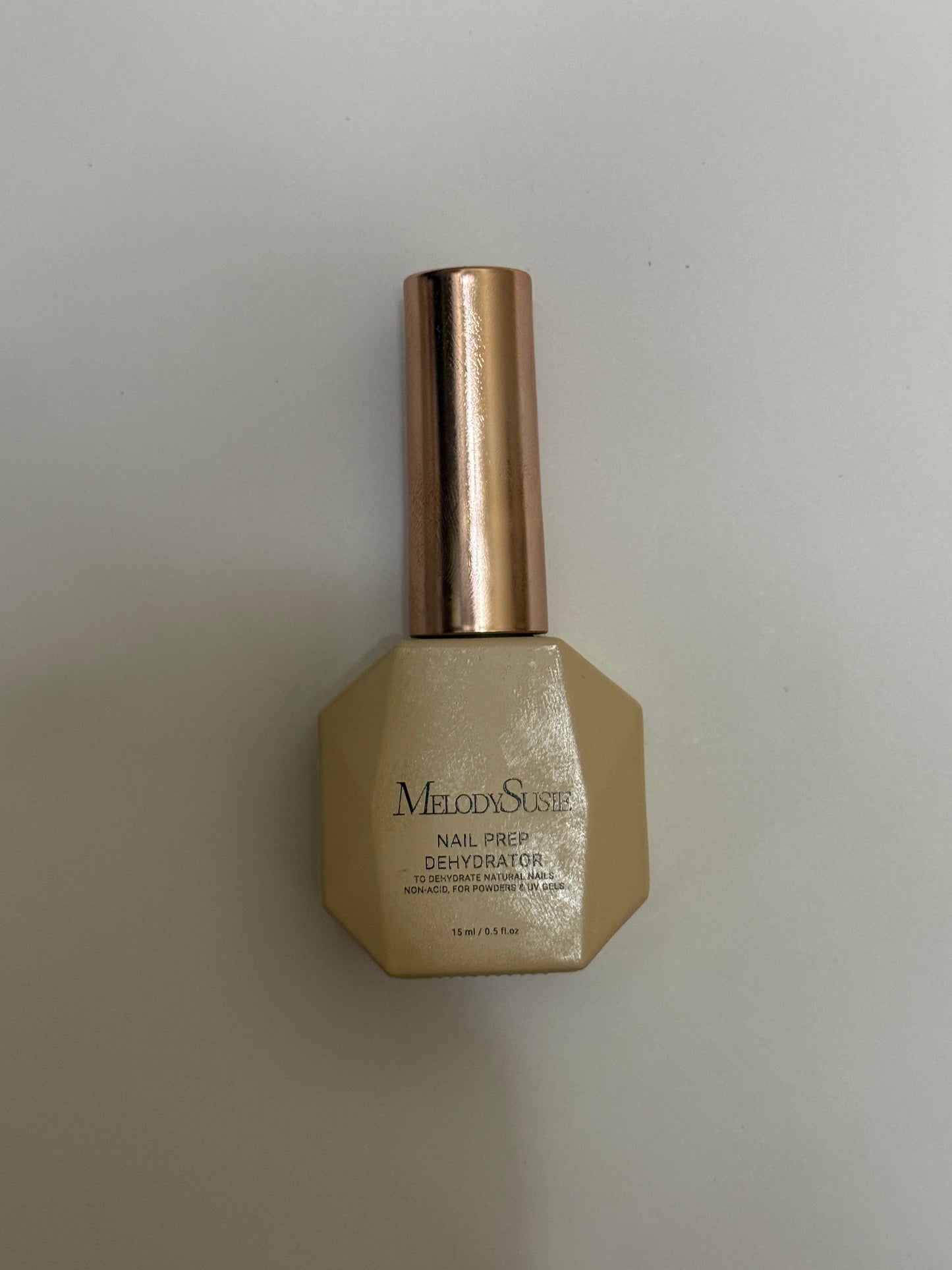 Gold bottle with bronze cap on a light gray background